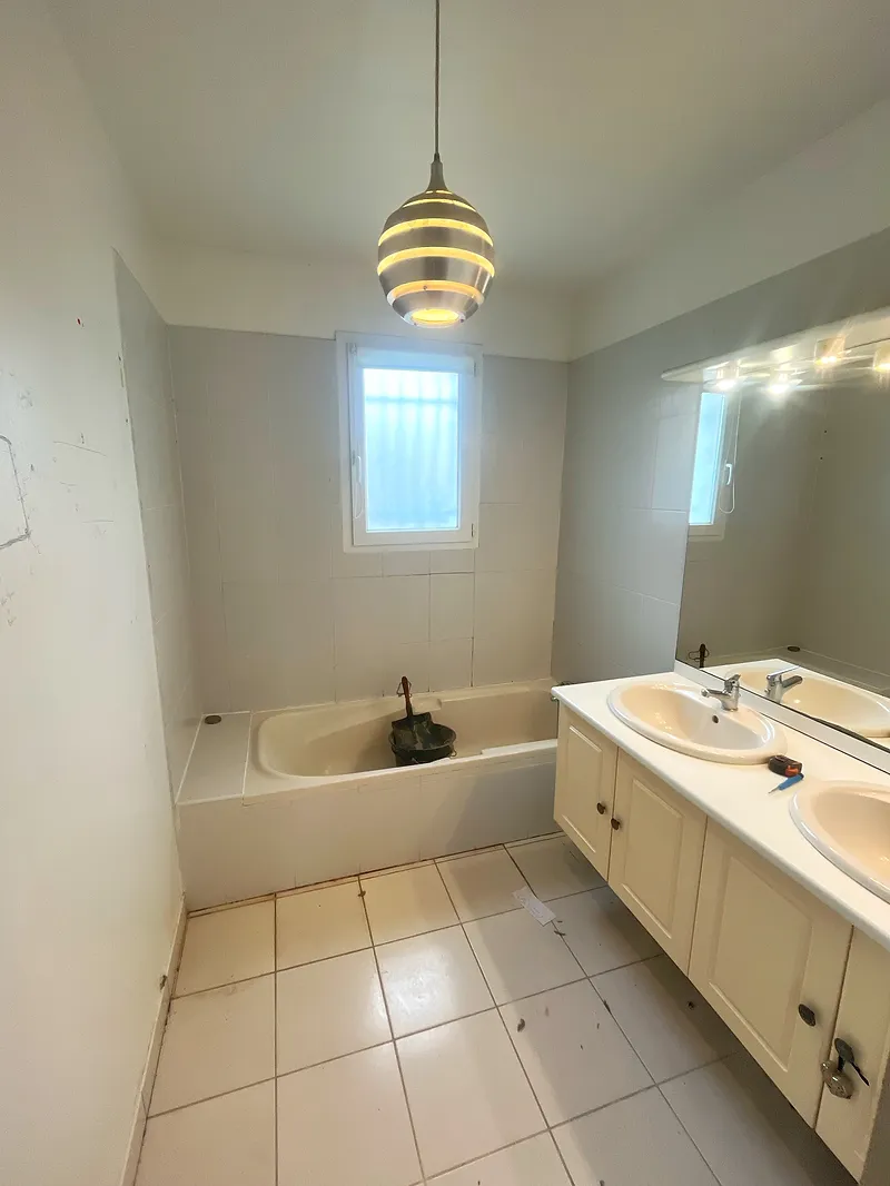 Avant rénovation : salle de bain d’origine avec baignoire encastrée et double vasque datée