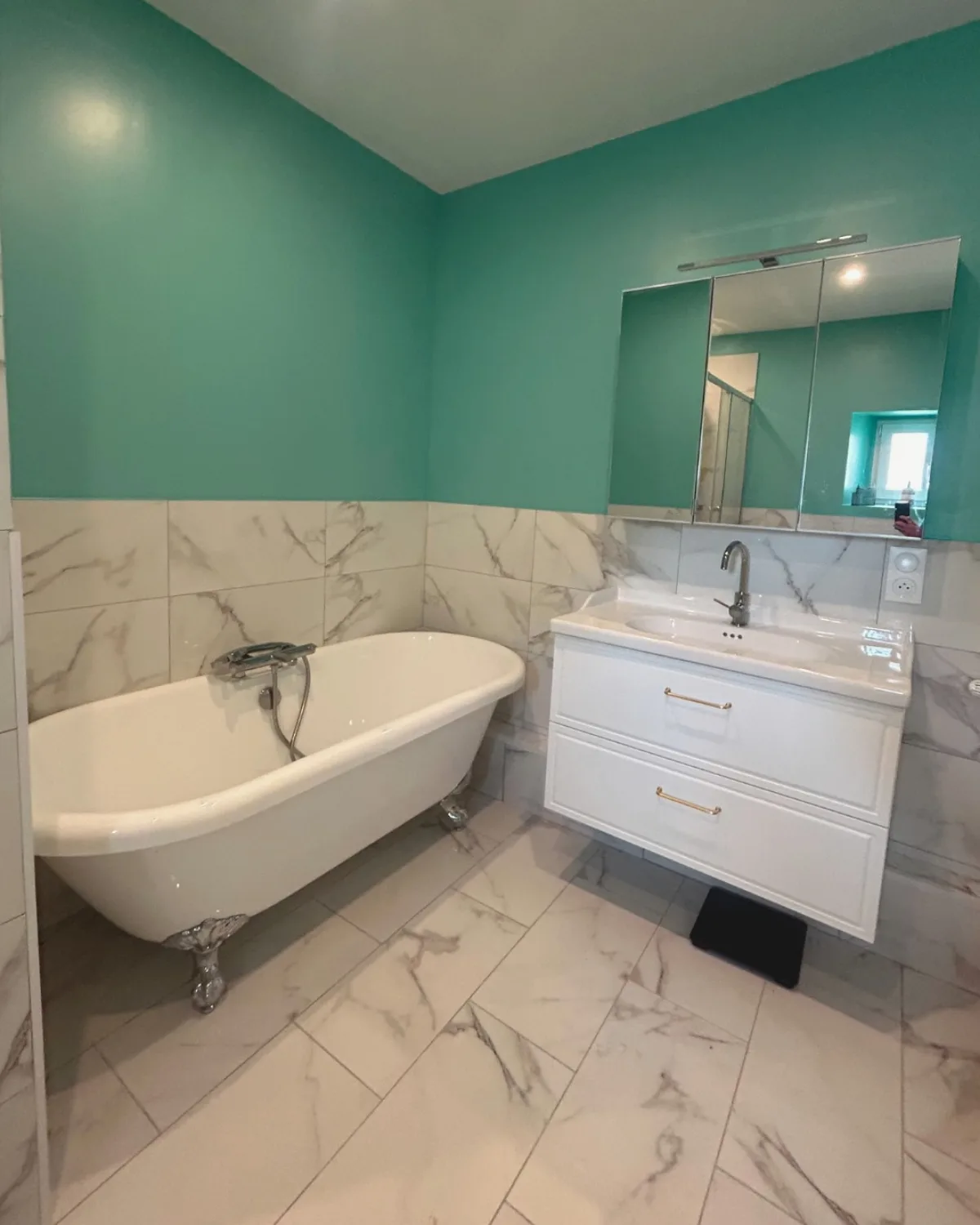 Salle de bain rénovée par RECB82 : carrelage effet marbre, baignoire îlot et meuble vasque blanc