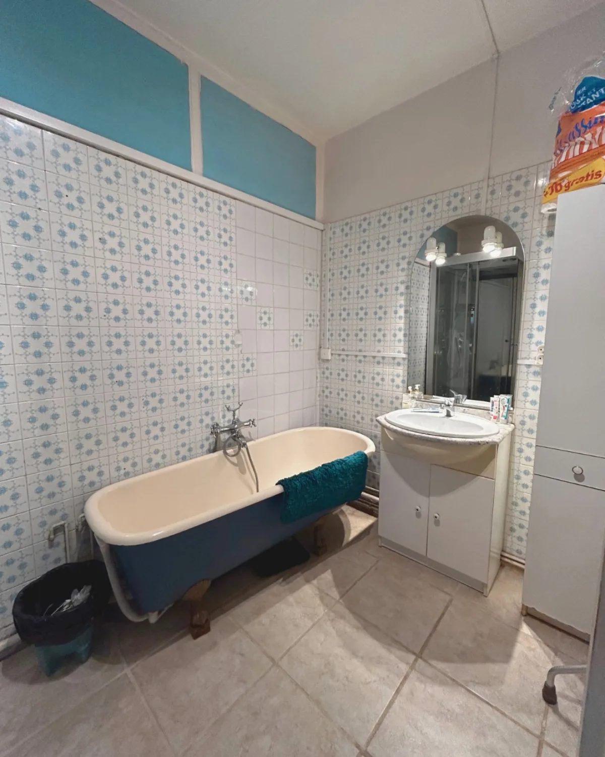 Avant : salle de bain d’époque, faïence bleue à motifs, baignoire sur pieds et meuble vasque usé